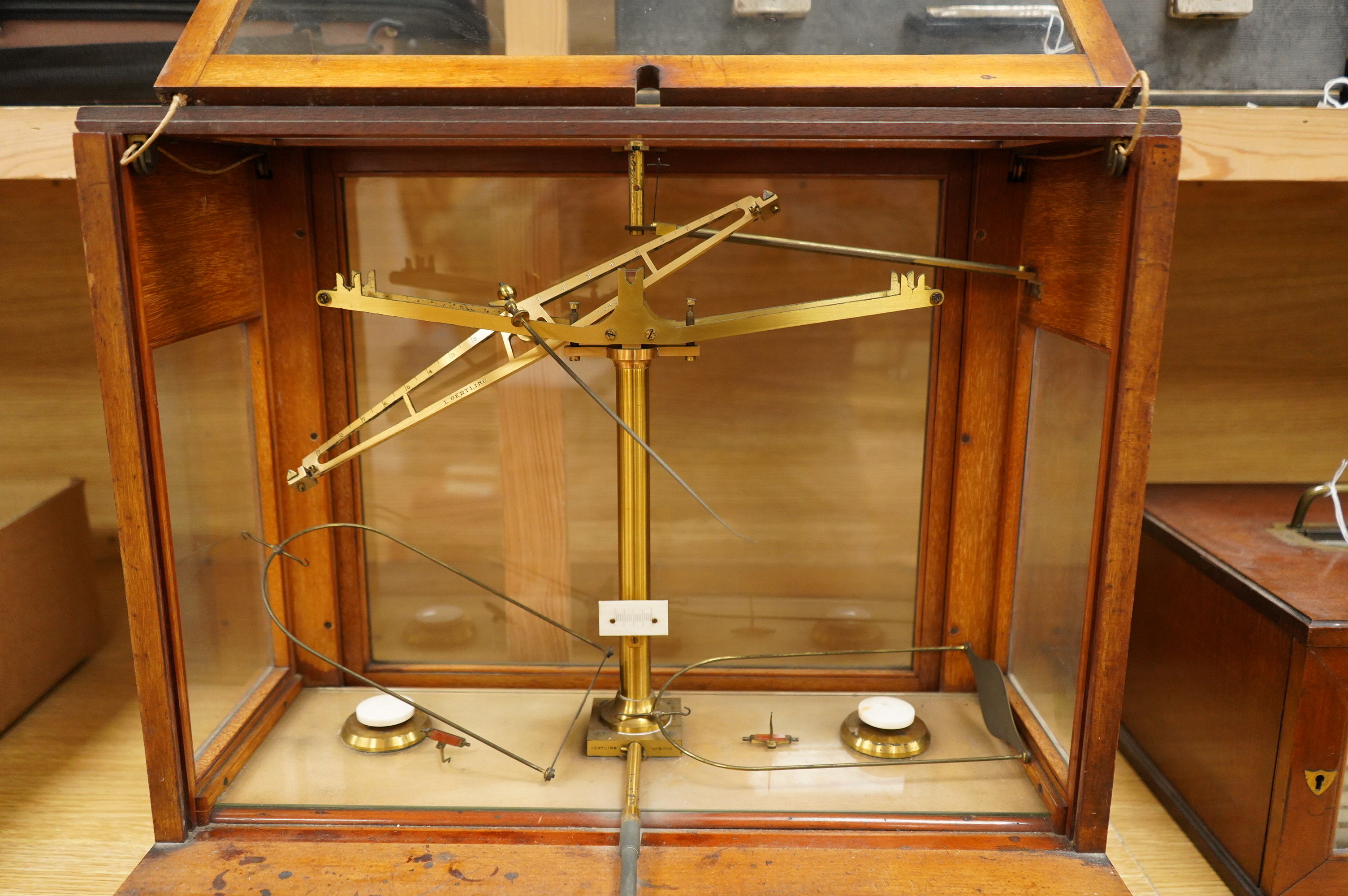 An early 20th century glazed mahogany cased laboratory chemical balance by Oertling, London, the drawer housing a set of weights, 45.5cm high, 50cm wide, 26cm deep